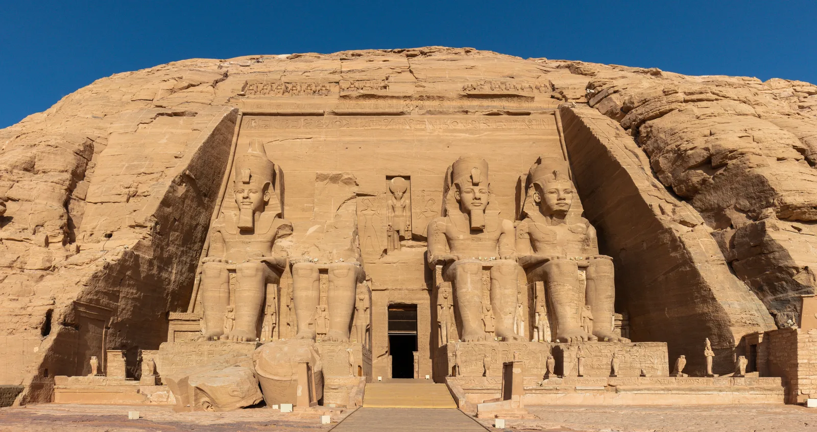 واجهة معبد أبو سمبل الكبير المنحوتة في الجبل وتماثيل رمسيس الأربعة الجالسة تحت سماء زرقاء